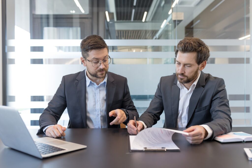 Business executives reviewing merger and acquisition agreements, financial documents, and transaction terms